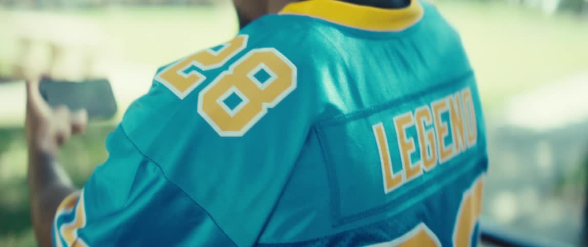 Man wearing a blue sports jersey holding a smartphone