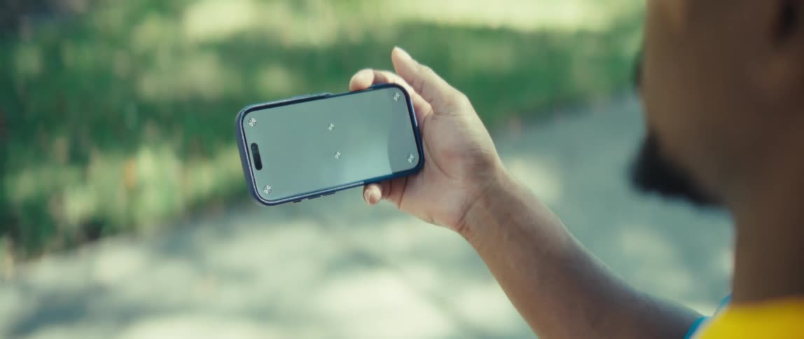 Man standing outside near the sidewalk views his smartphone