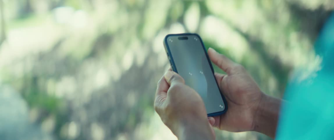 Close up of a young black man using a mobile phone while walking outdoors during daytime