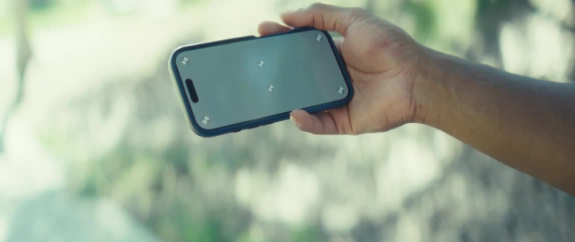 Person holds a smartphone horizontally in a bright outdoor setting