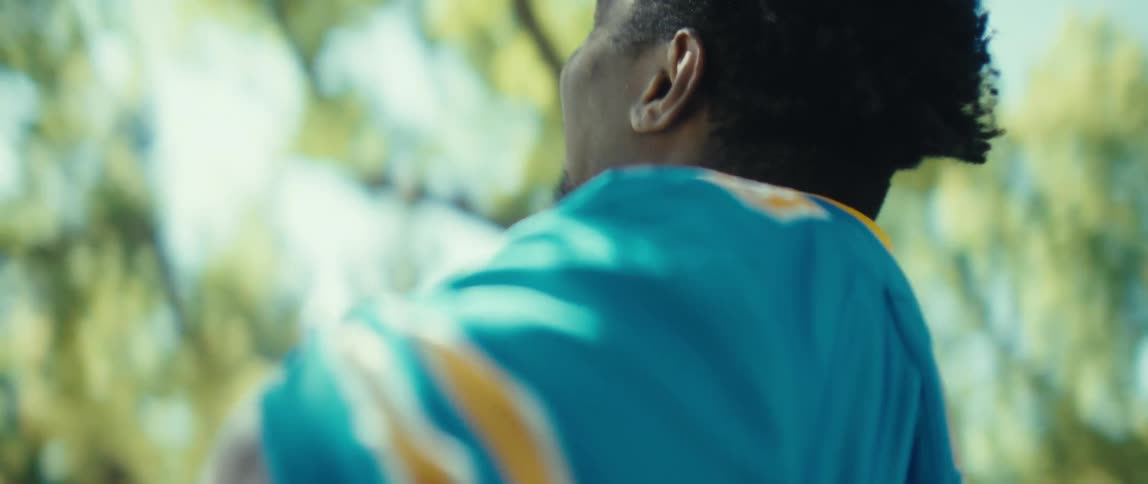 The video is a wide steady shot of a person standing against a wall covered in street artgraffiti holding a can of spray paintthe person wearing dark loosefitting clothes is looking at the colorful mural they are presumably working on or
