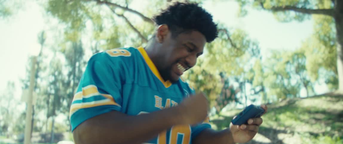 The man cheers and kisses his jersey while looking at his cell phone