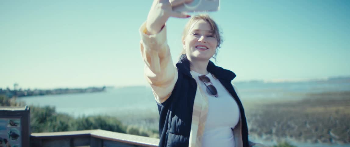 The woman is taking a selfie by the lake