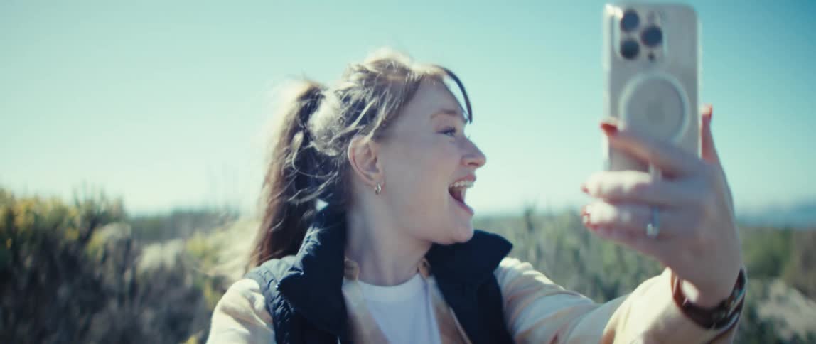 Woman smiling while on a video call outdoors under a blue sky