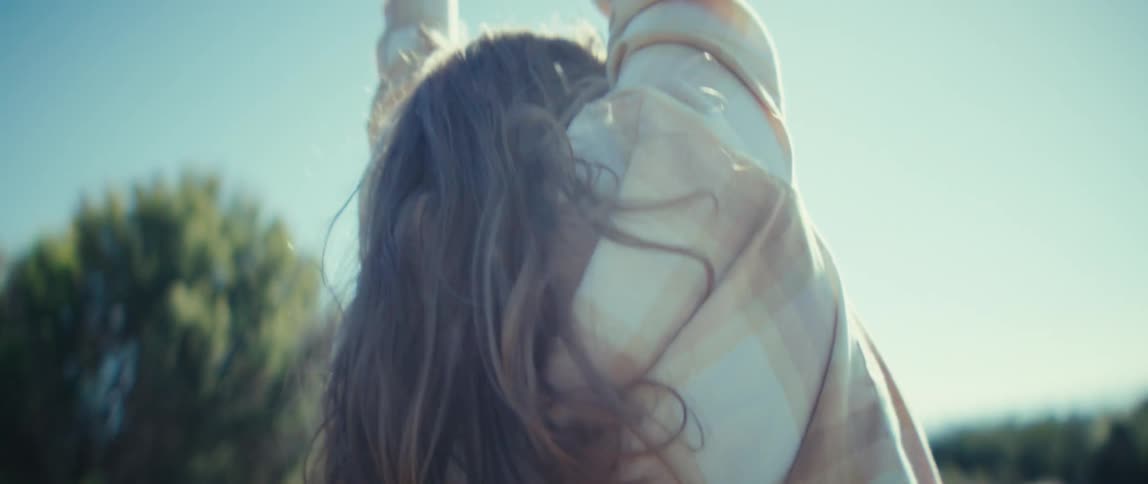 Woman stretches facing a coastal landscape under a clear sky