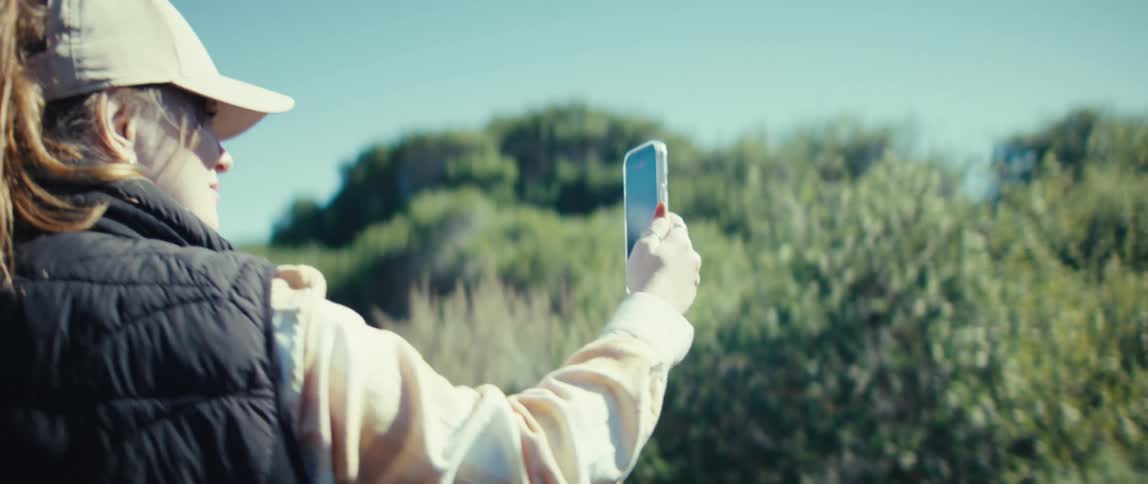 The woman records with her cell phone as she hikes
