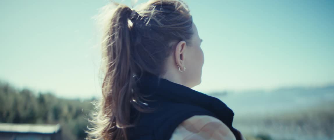 A woman closes her eyes as she lets the breeze hit her face from off the water