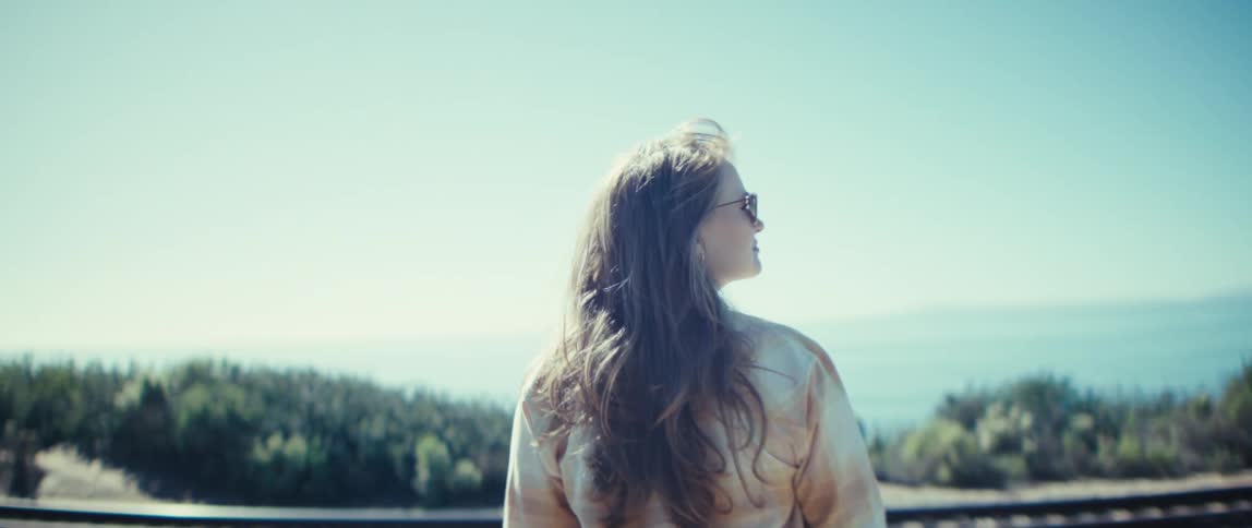 The woman is looking at the sky while wearing sunglasses