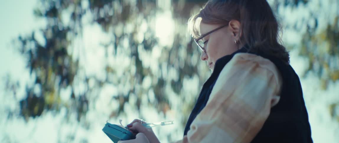 A woman outdoors drawing in a small sketchbook