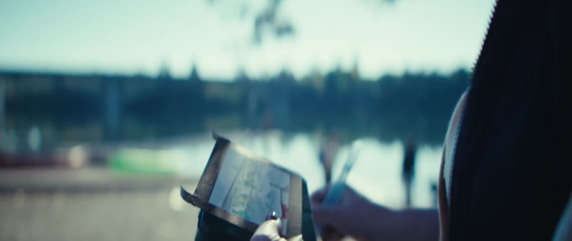 A woman is drawing on a canvas as she sits at a lake beach area