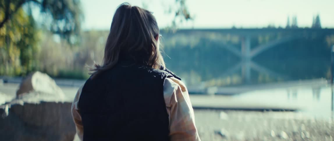 The woman is standing by the lake on a sunny day