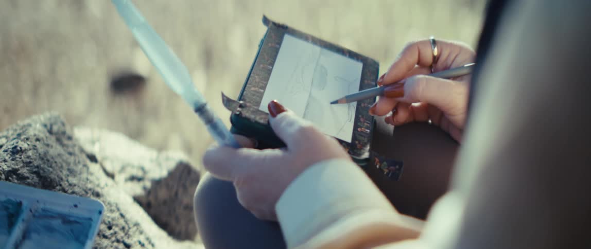 The woman is sketching with a pencil