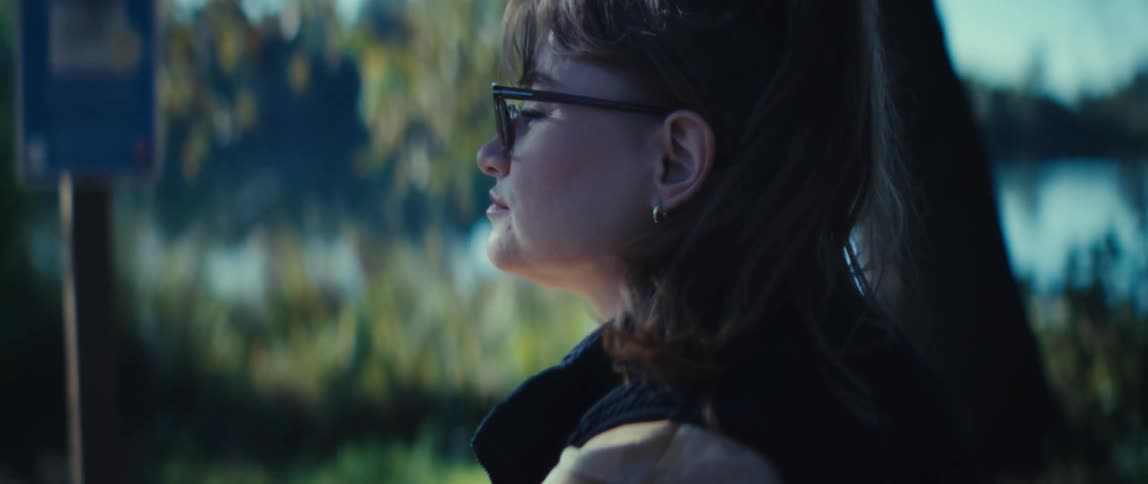 Woman sitting on the ground near the water looks up to watch the scenery