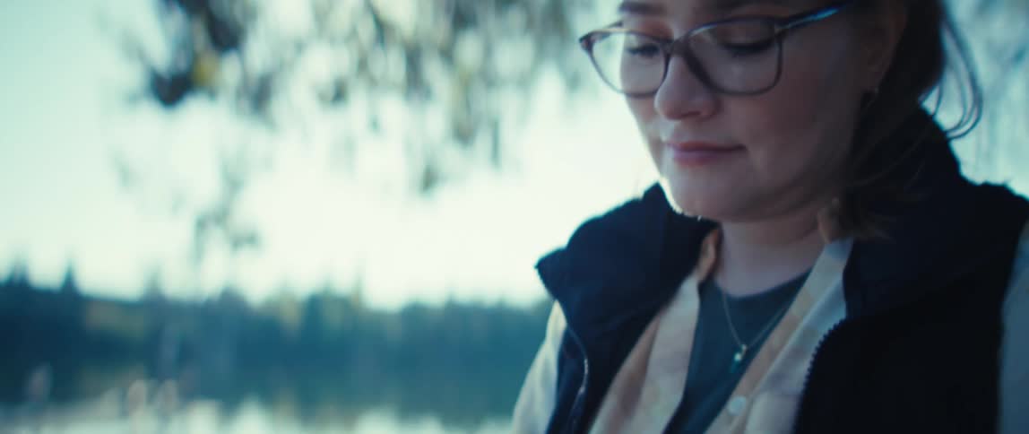 Person writes on a tablet near a lake