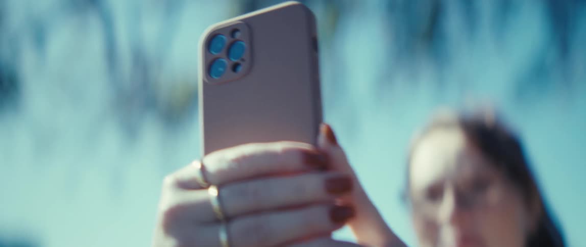 Woman holds a beige smartphone up under sunlight