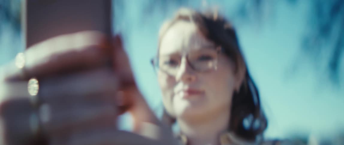Woman wearing glasses smiles under natural sunlight on a clear day