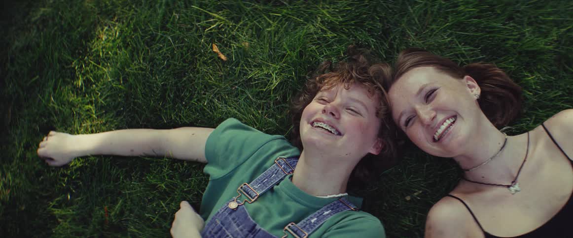 Two people lying on the grass smile enjoying the moment