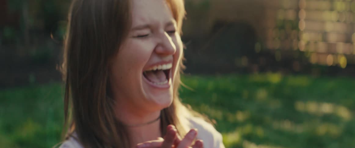 Woman laughing joyfully in an outdoor setting