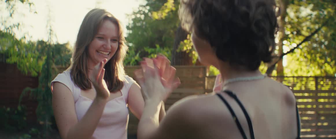 Two sisters play a hand clapping game together in the backyard at sunset