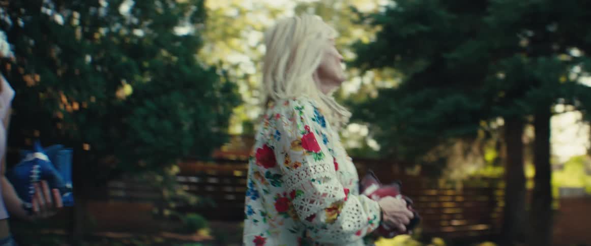 Woman smiles while tossing colorful bags in a backyard