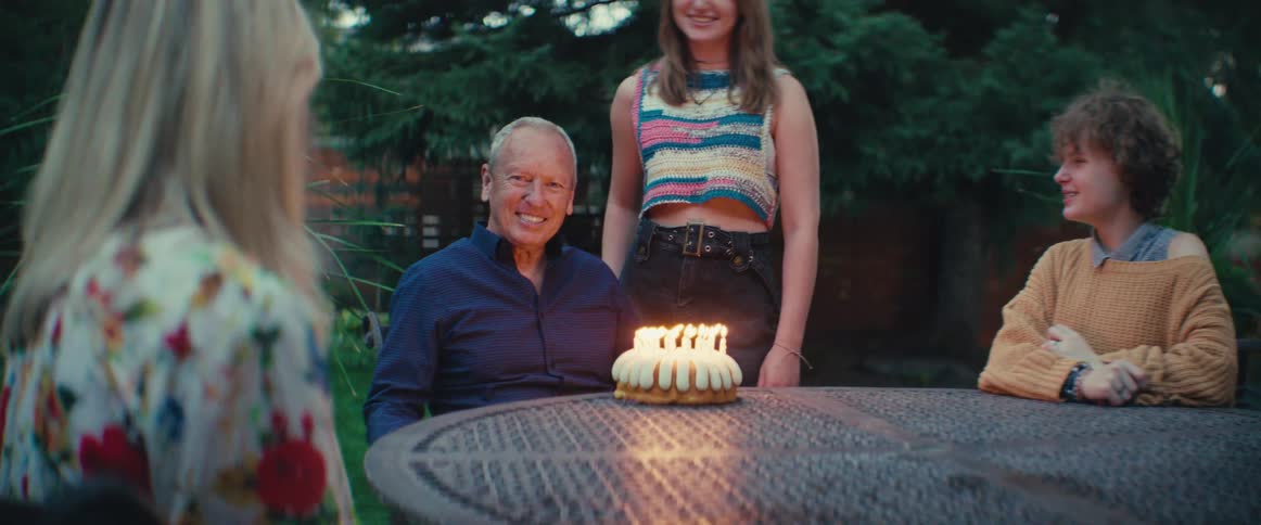 A family happily celebrates a birthday party in the backyard at dusk