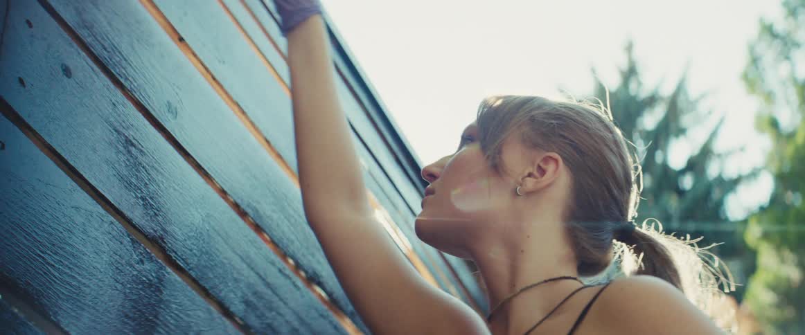 A young woman painting a wooden wall with a brush