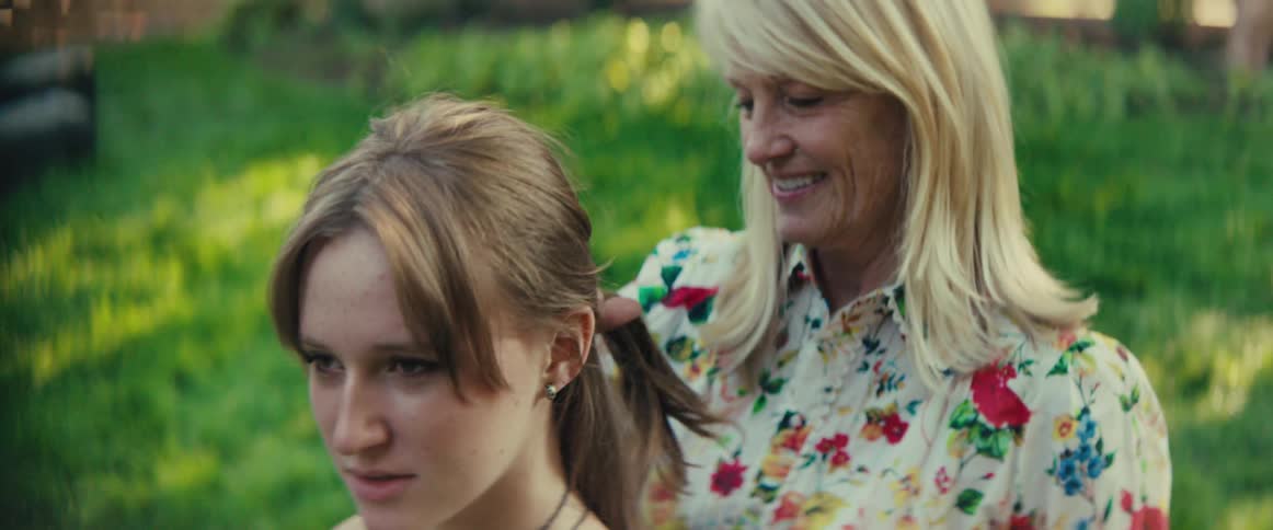A woman takes out the ponytail in another womans hair then rakes her fingers like a brush