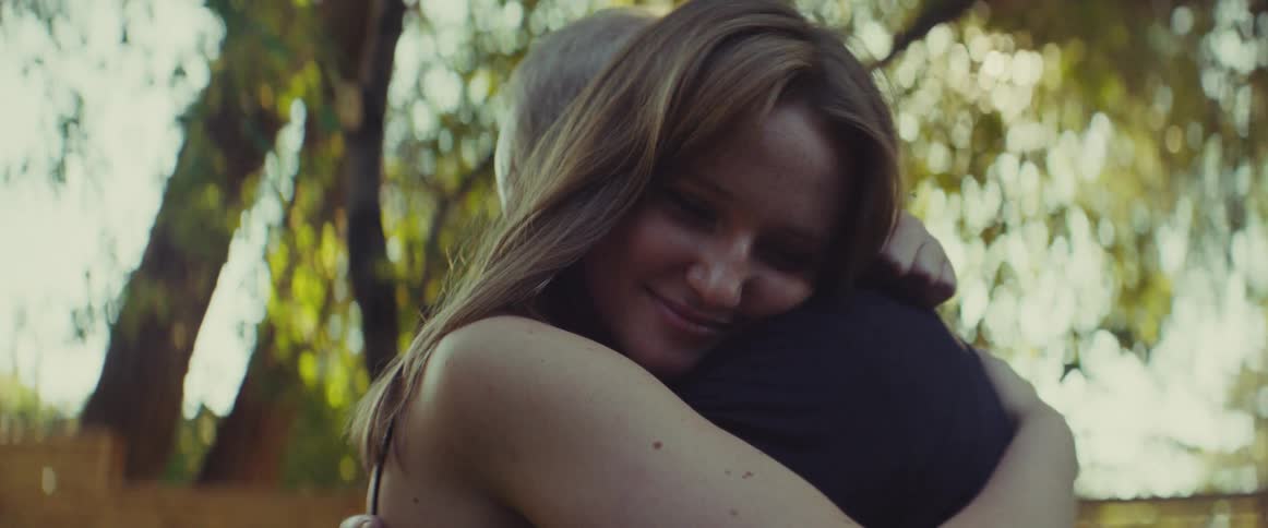 The man and woman are hugging in the yard