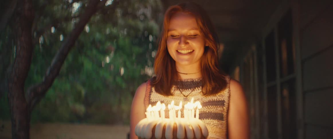 The woman sings happy birthday as she brings out the cake