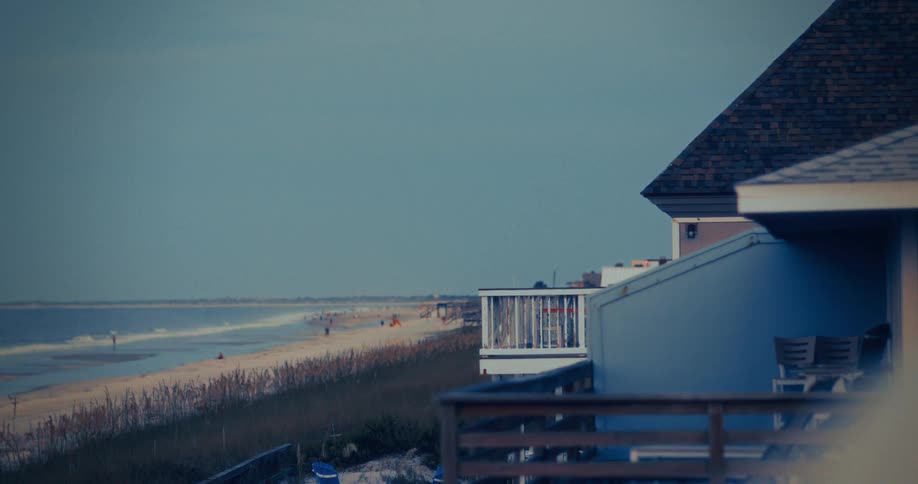 A building stands by the shoreline as waves crash against it at sunset