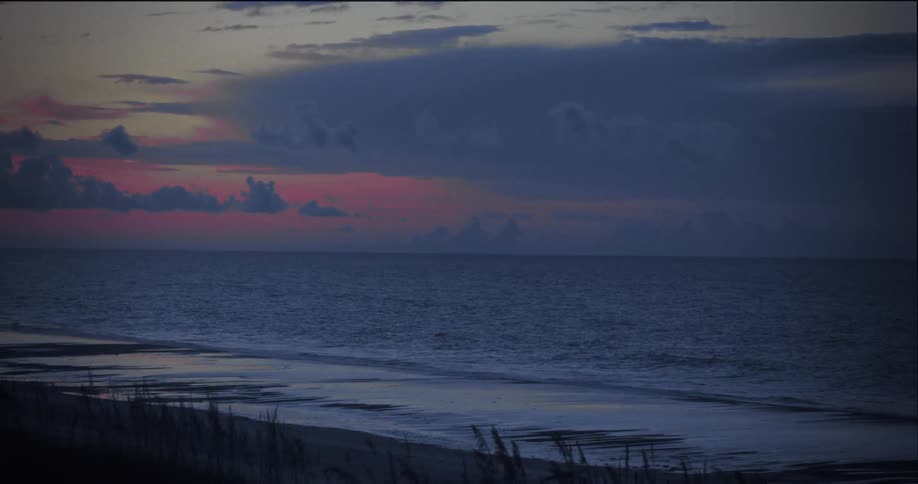 Waves roll into shore and over the beach at dusk