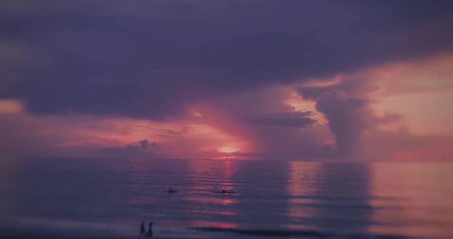 Colorful sky reflected on the sea at sunset with people in kayaks