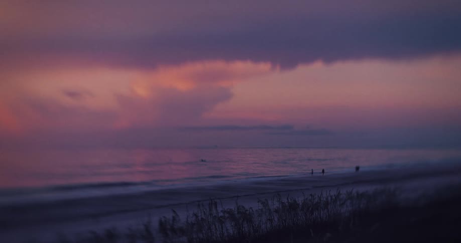 People are standing on the beach at sunrise