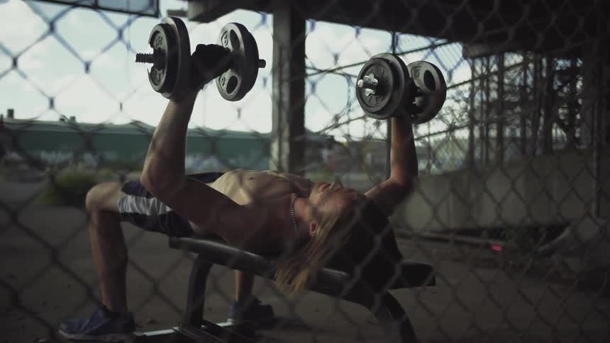 A man lifts two weights above his chest