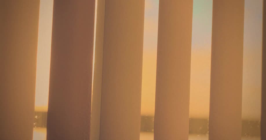 Close up of window vertical blinds opening to sunlight in the morning