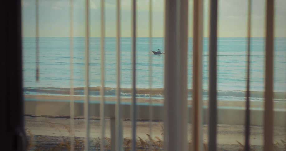 Boat sailing on the sea seen through blinds