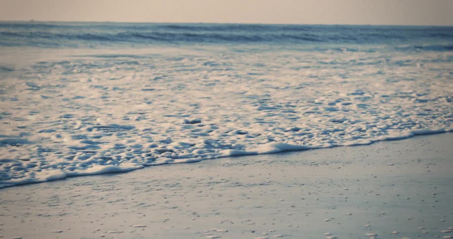 Waves turn to froth as they hit the beach