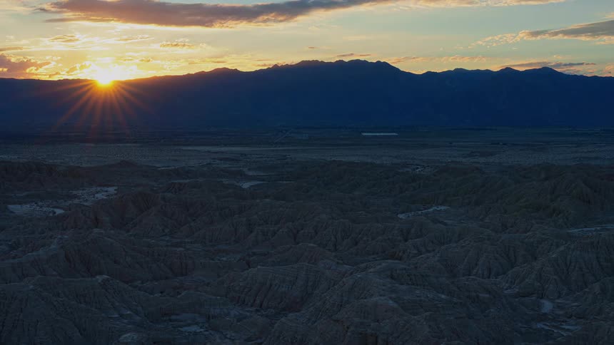 Time lapse of sun setting over the horizon below the mountains