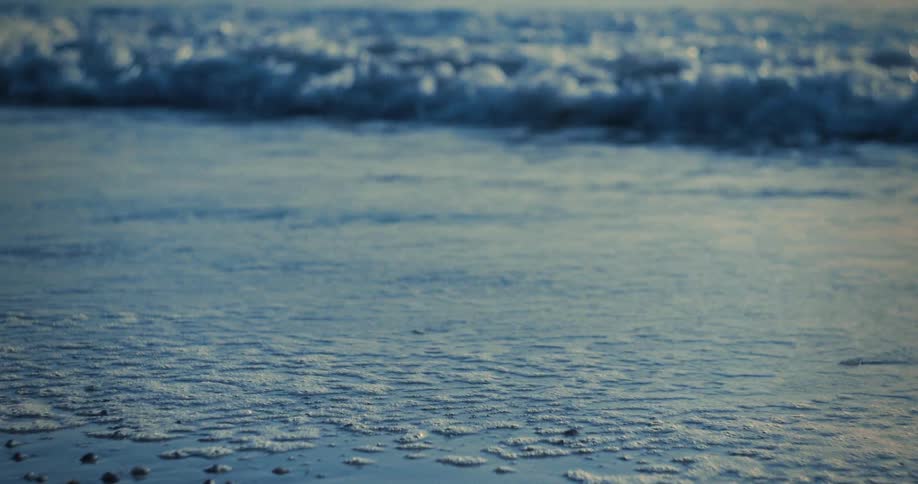 Gentle waves breaking on the shore at sunset