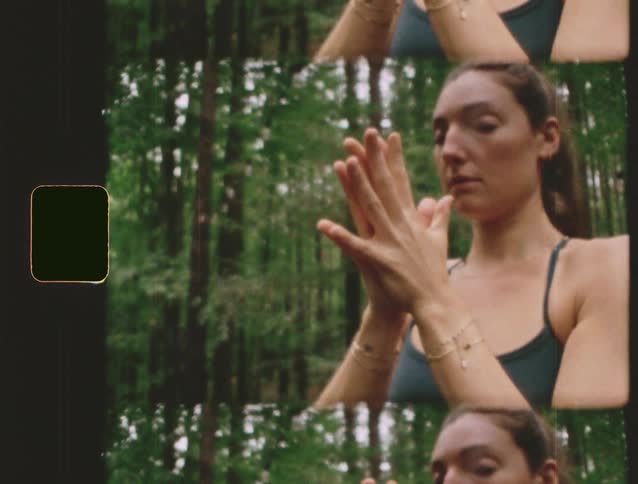 A young woman practices yoga in the woods on a mat at midday