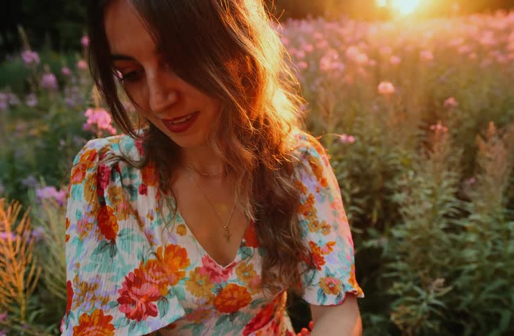 The woman is standing in the field of flowers