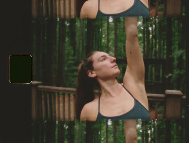 A young woman practices yoga on the porch of a building in the woods at midday