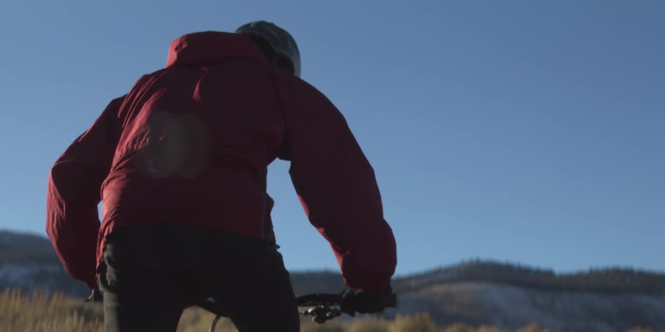 The man is riding his mountain bike towards the mountain