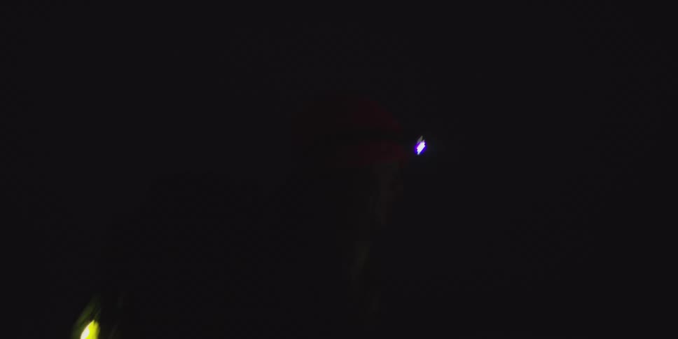 Person holding lit flashlight in dark setting with central light beam