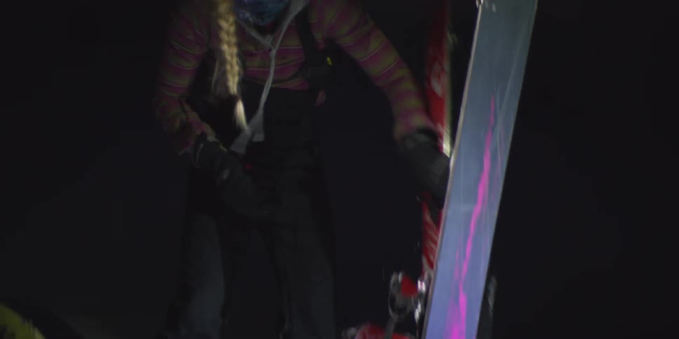 Skier adjusting equipment at night with a headlamp