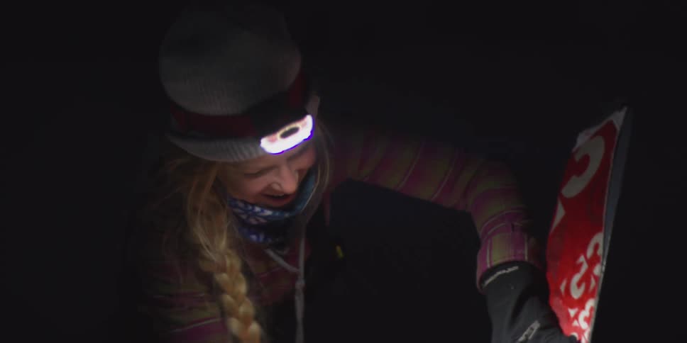 Woman smiling while holding a ski illuminated at night