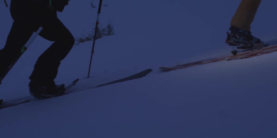 Skiers ascend a snowcovered slope at dawn