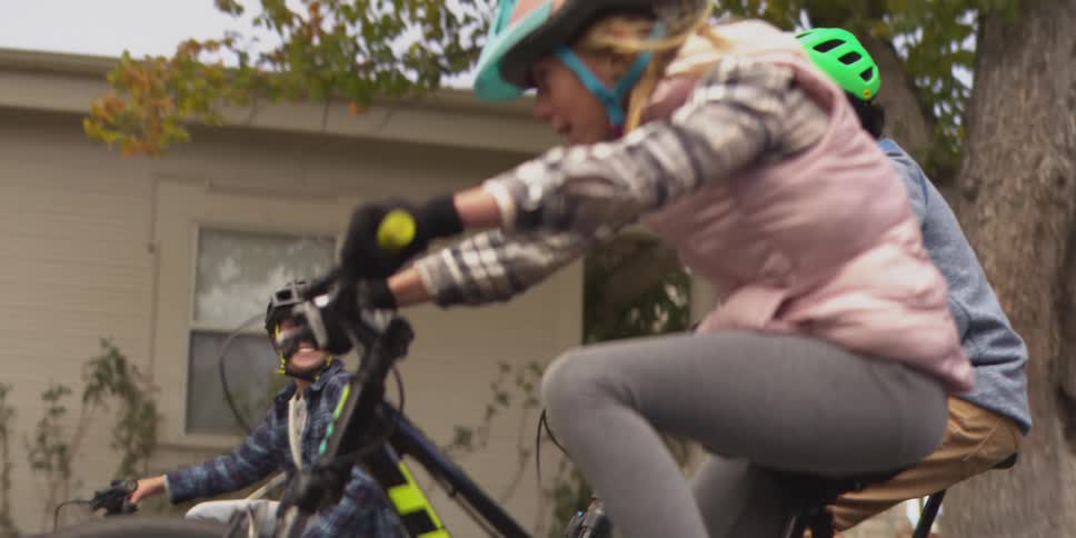 A group of kidstwo boys and a girlride their bicycles in the middle of a suburban street enjoying a fun time together