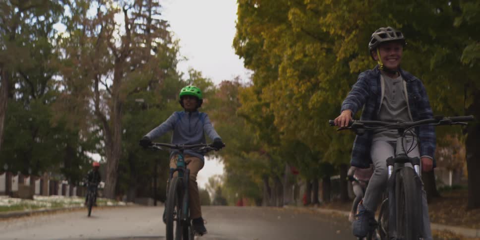 Four children riding bicycles on city streets one of them riding without holding the handlebars