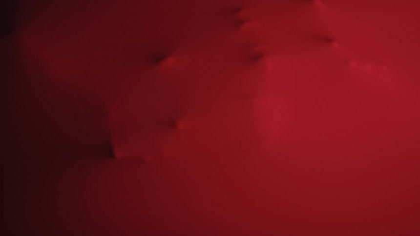 The video shows an abstract background of dark red and black color gradients that move and shift subtly the dark red seems to swell up from the bottom and then recede back into the blackness creating a moody minimalist texture009